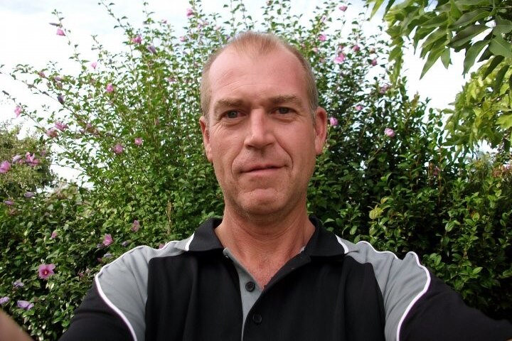 Selfie image of a man with short hair wearing a black and grey polo shirt