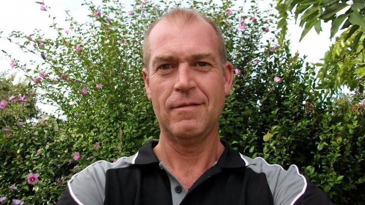 Selfie image of a man with short hair wearing a black and grey polo shirt.