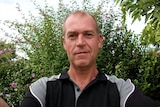 Selfie image of a man with short hair wearing a black and grey polo shirt.