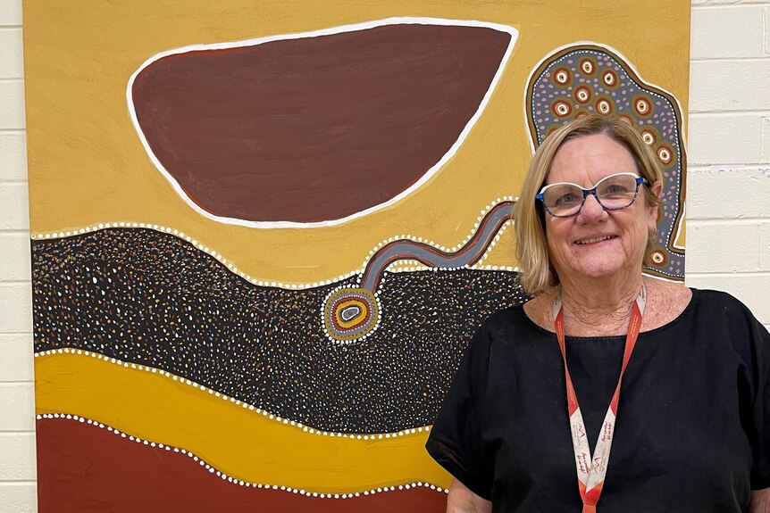 A woman standing in front of an aboriginal painting