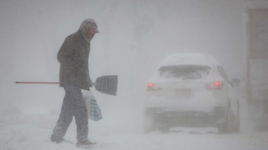 A man crosses a street in whiteout conditions during a winter storm in Buffalo.