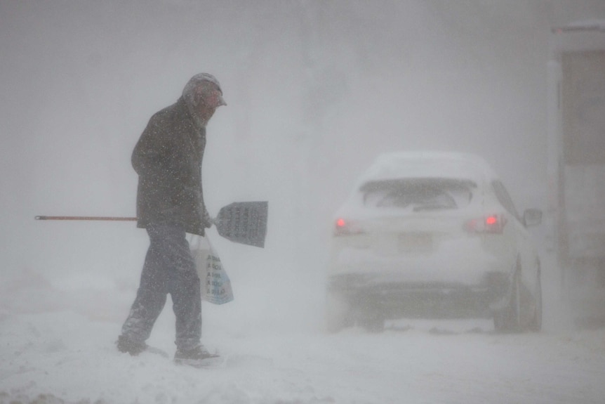 A man crosses a street in whiteout conditions during a winter storm in Buffalo.