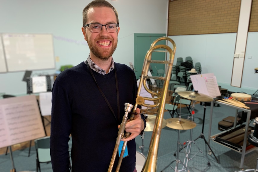 Tutor Tim Walsh holds a trombone in a music rehearsal room.
