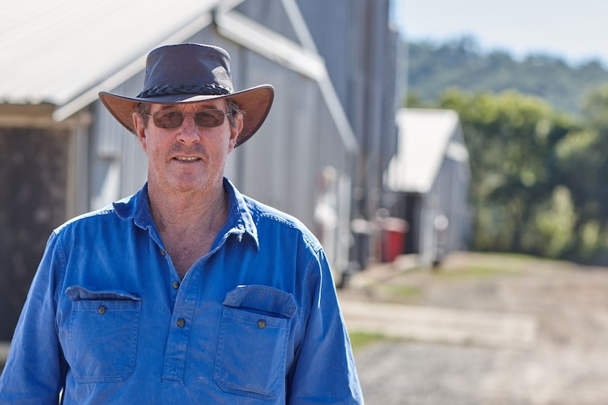 Chicken grower John Courtney in a hat and sunglasses out the front of his sheds