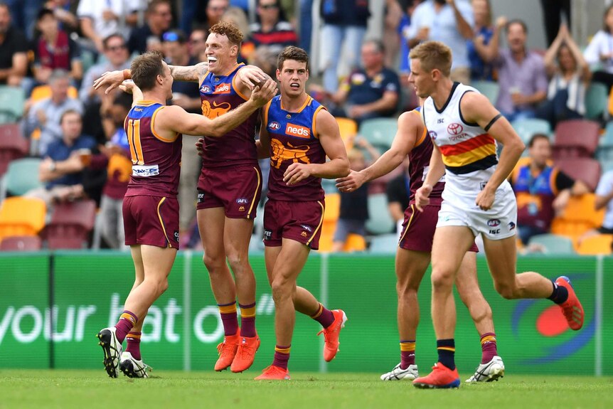 Mitch Robinson celebrates by jumping in the air with his arms wide as his teammates run towards him