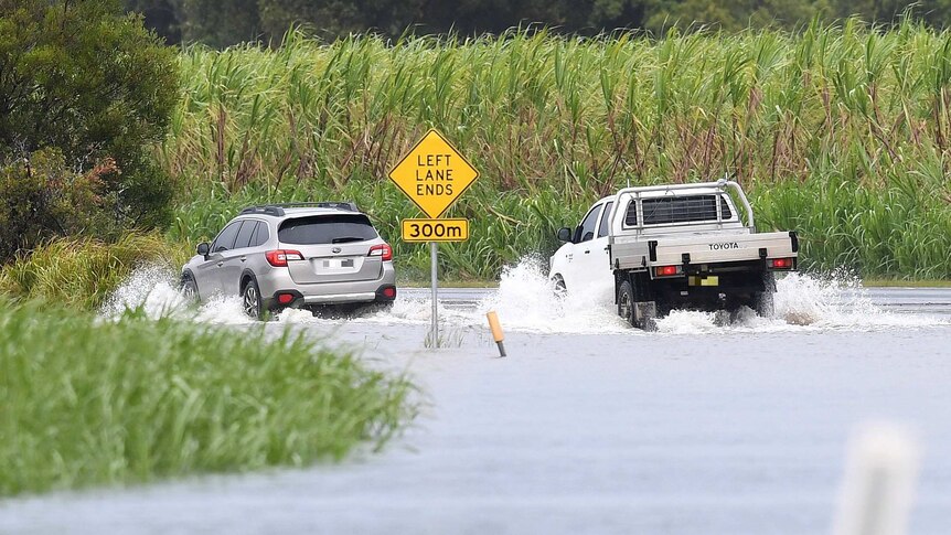 Cars drive through floodwaters at Tumbulgum.
