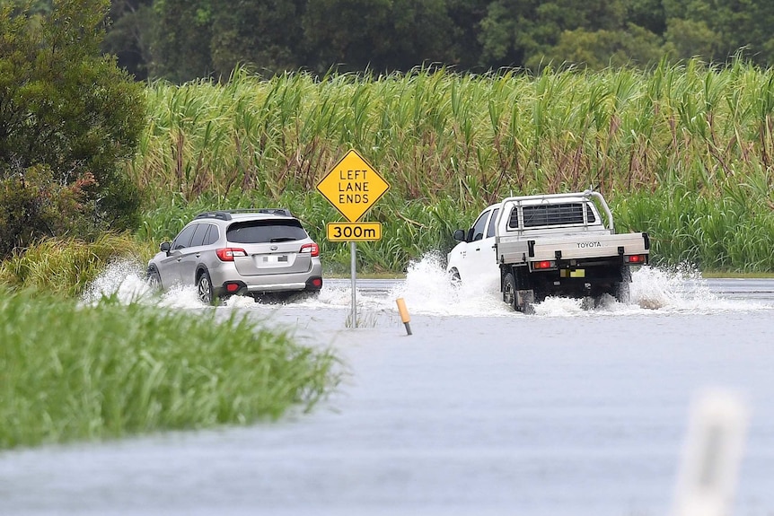 Cars drive through floodwaters at Tumbulgum.