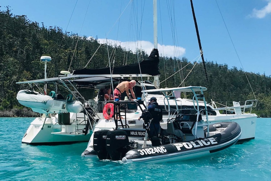 Bruce Piggot leaning over his yacht, which is on Cid Harbour, speaking to police in a boat.