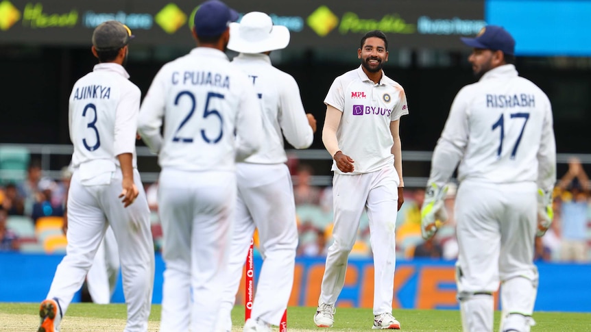 Indian bowler Mohammed Siraj smiles as his teammates approach him after another Test wicket against Australia.