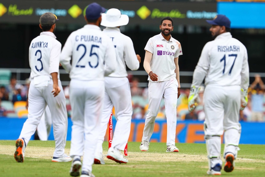Indian bowler Mohammed Siraj smiles as his teammates approach him after another Test wicket against Australia.