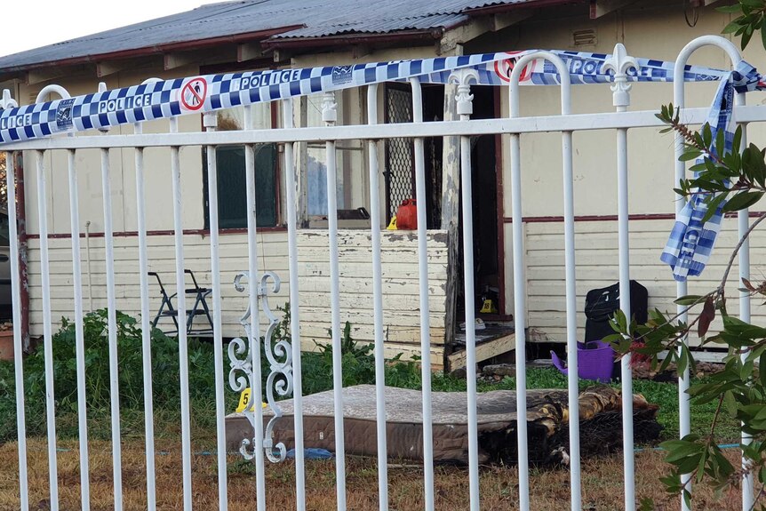 A charred mattress is seen out the front of a house.