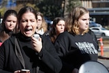 A woman yells into a microphone at a protest at the Australian National University.