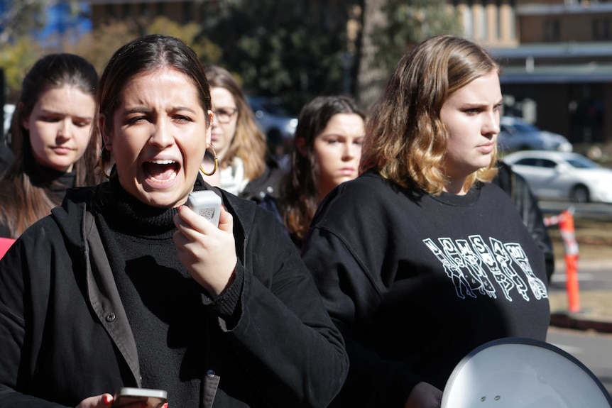 A woman yells into a microphone at a protest at the Australian National University.