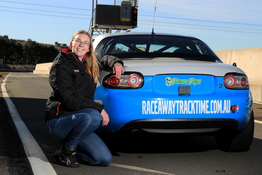 Woman smiling next to race car