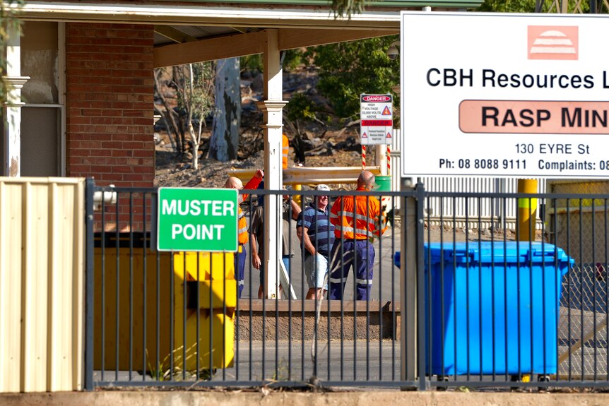 A sign reading "CBH Resources Limited Rasp Mine". Workers can be seen gathered behind it.