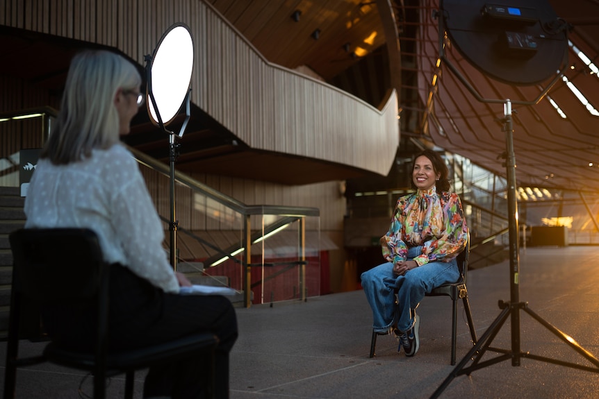 Woman having her photo taken on chair looking into lens 