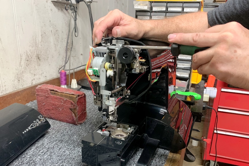 Close up of hands fixing an old sewing machine