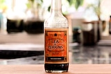 A bottle of Worcestershire sauce sits on a board.