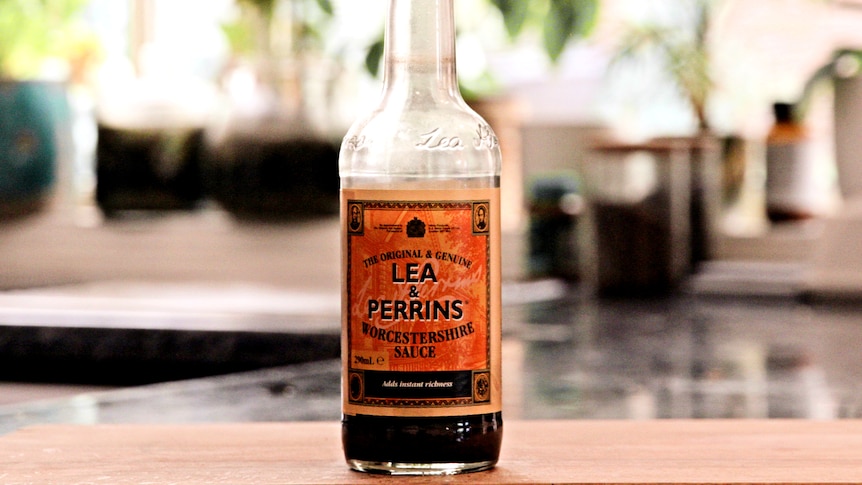 A bottle of Worcestershire sauce sits on a board.