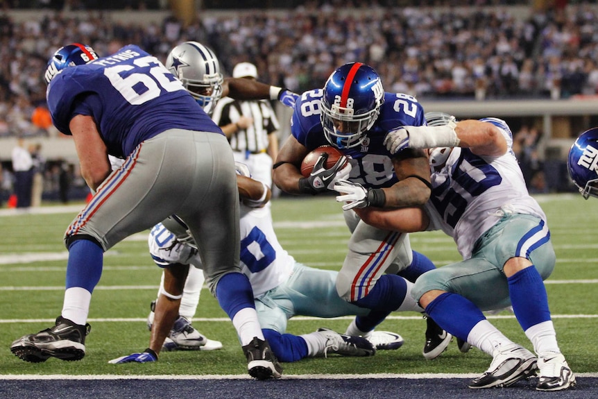 A New York Giants player scores a touch down as line backer Mitch Petrus makes a block to let his teammate through