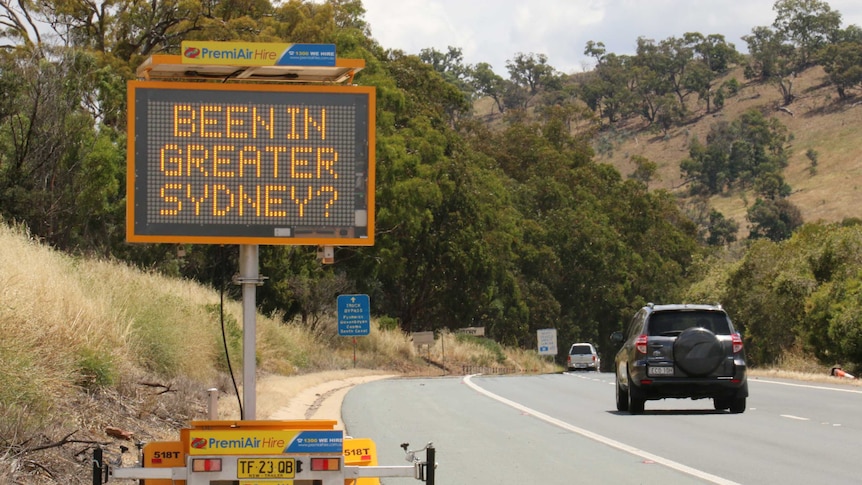 A neon sign on the side of the road asks 'Been in Greater Sydney?" as cars drive towards the capital.