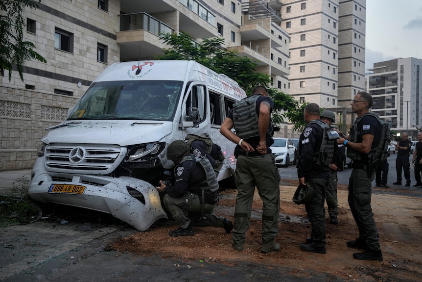 Members of Israeli bomb squad inspect a car that was hit by a rocket fired from the Gaza Strip.
