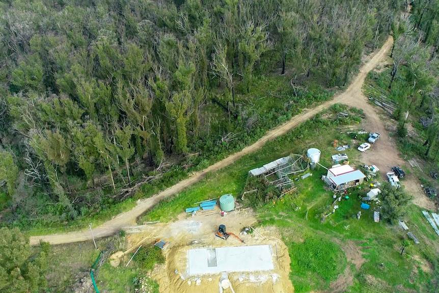 An aerial shot of a property in a forest with a new concrete pad