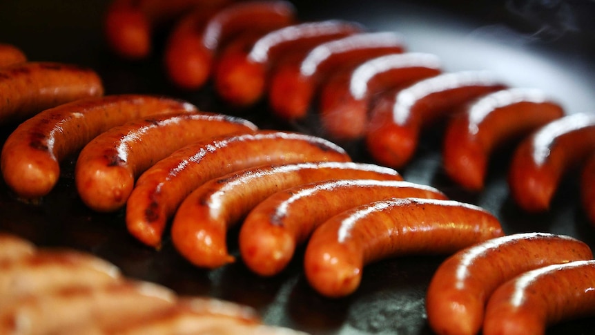 Tight shot of cooked sausages on a barbecue.