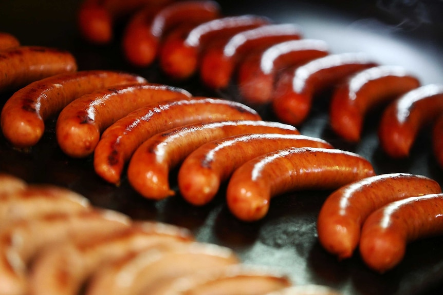 Tight shot of cooked sausages on a barbecue.