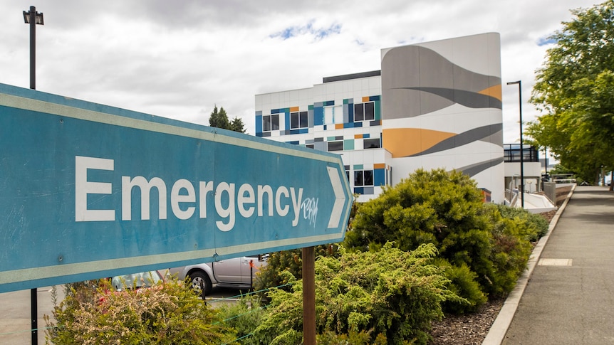 A sign saying emergency pointing towards a colourful building.