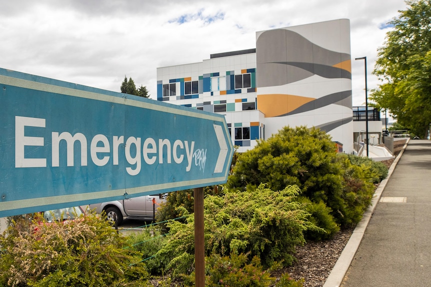 A sign saying emergency pointing towards a colourful building.