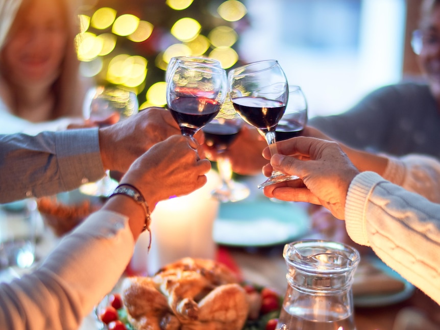 Glasses of wine being toasted over a Christmas lunch