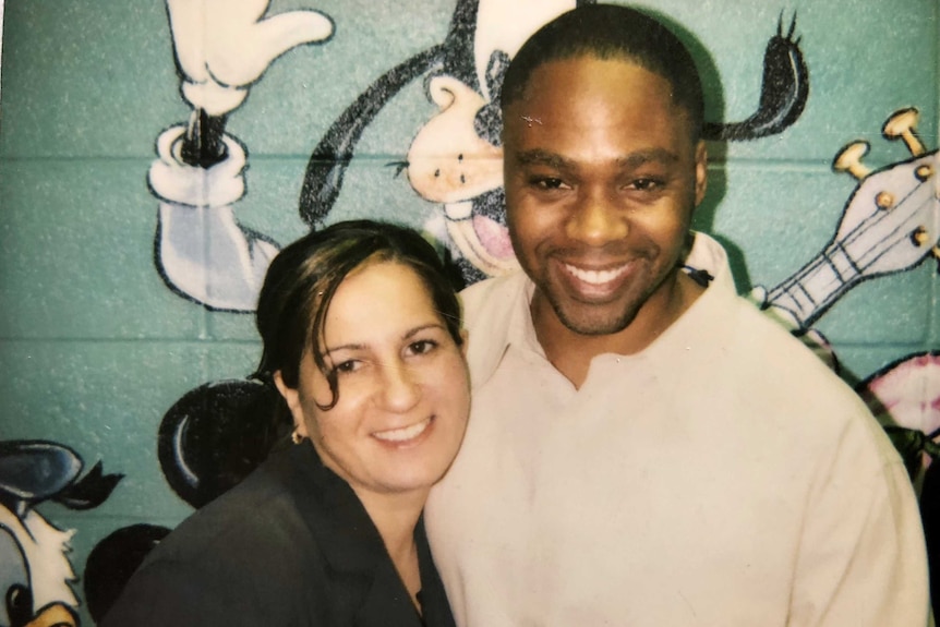 Louise and Valentino Dixon hug and smile in front of a wall