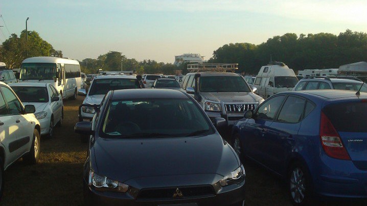 Cars parked in rows along a lawn at the beach.