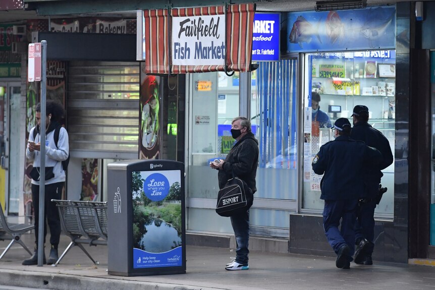 Two police officer walk through a shutdown shopping district in Fairfield, in Sydney's south west. 