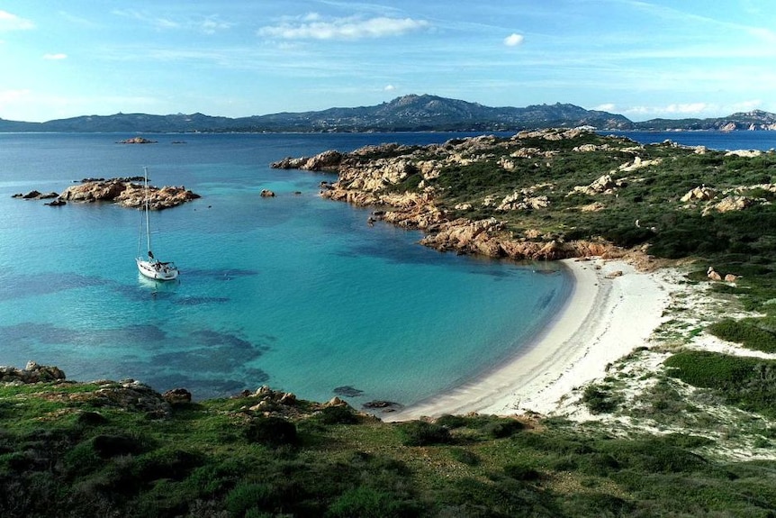 An aerial shot of an island surrounded by crystal blue waters.