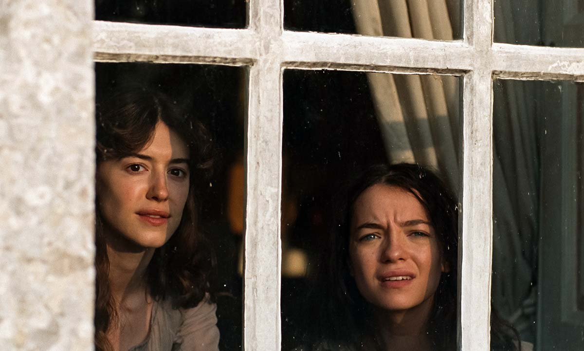 two sisters look out a window