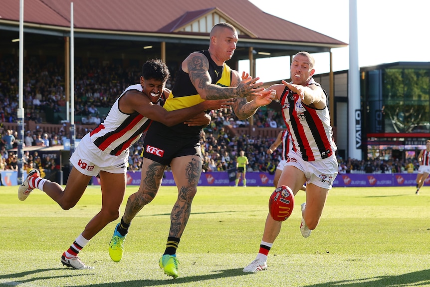 Nasiah Wanganeen-Milera of the Saints and Callum Wilkie of St Kilda try to stop Richmond's Dustin Martin during an AFL game.