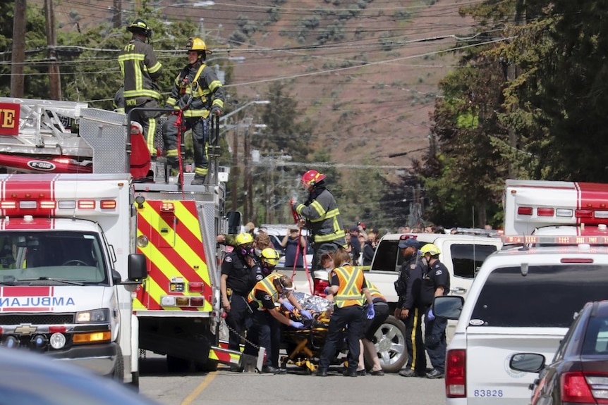 First responders transport an injured person on a stretcher at the scene of a crash.