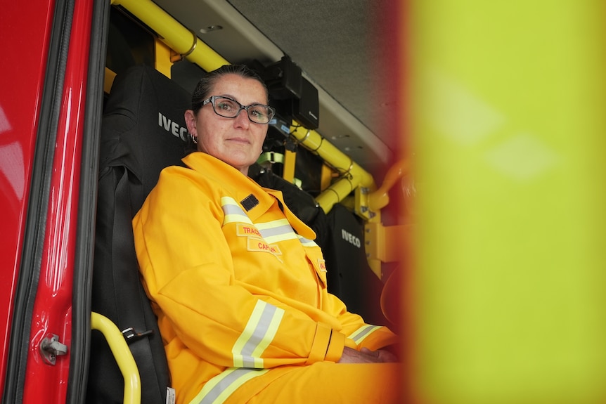 Tracey Johnston wears her firefighting uniform and sits in the back seat of a fire truck.