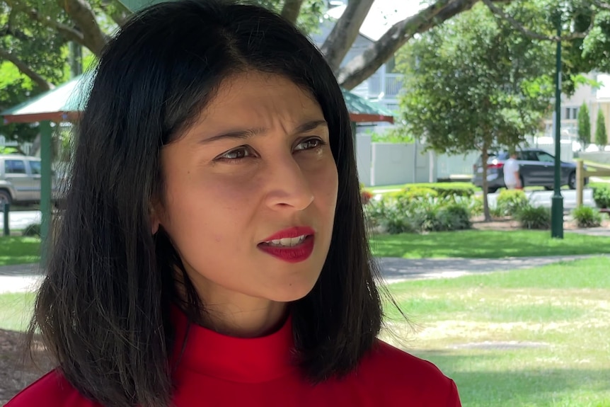 woman with shoulder length hair in red top speaking to camera