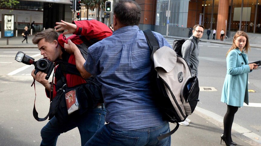 Former Australian Workers Union official, Bruce Wilson, attacks a photographer to avoid being photographed.