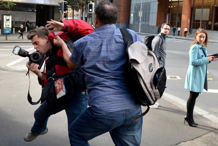 Former Australian Workers Union official, Bruce Wilson, attacks a photographer to avoid being photographed.