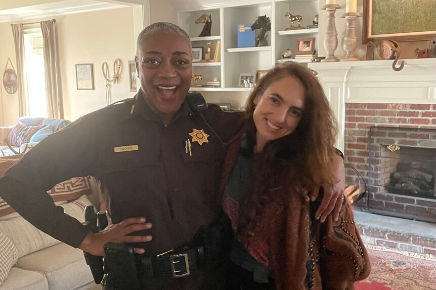 An actor wearing a police outfit stands next to a director. 