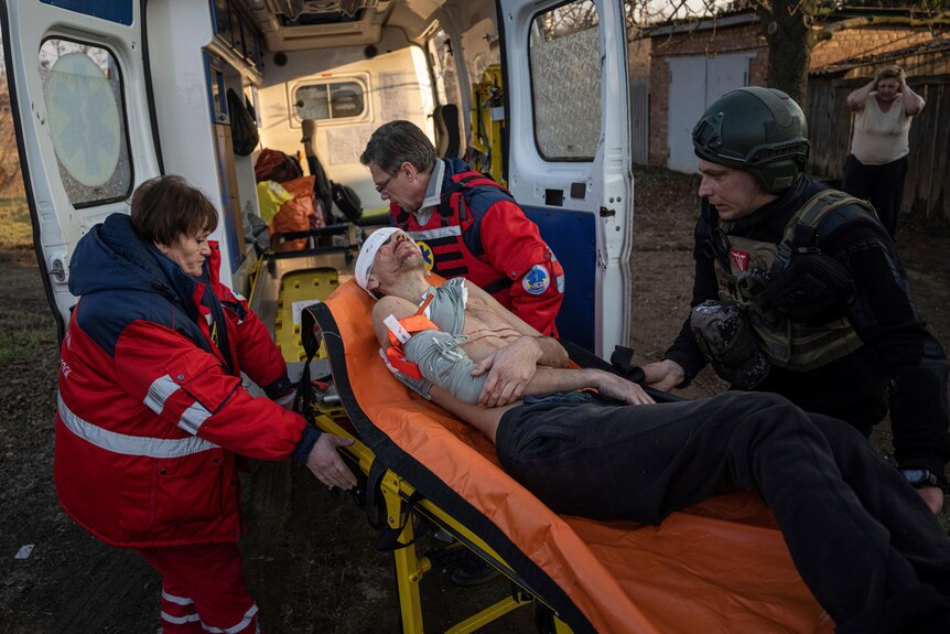 Paramedics and Ukrainian police officers haul a stretcher carrying an injured local resident.