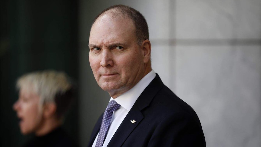 Neville Power standing outside Parliament House and glancing sideways.