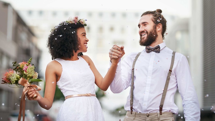 Trendy man with suspenders, beard and man bun marrying trendy woman
