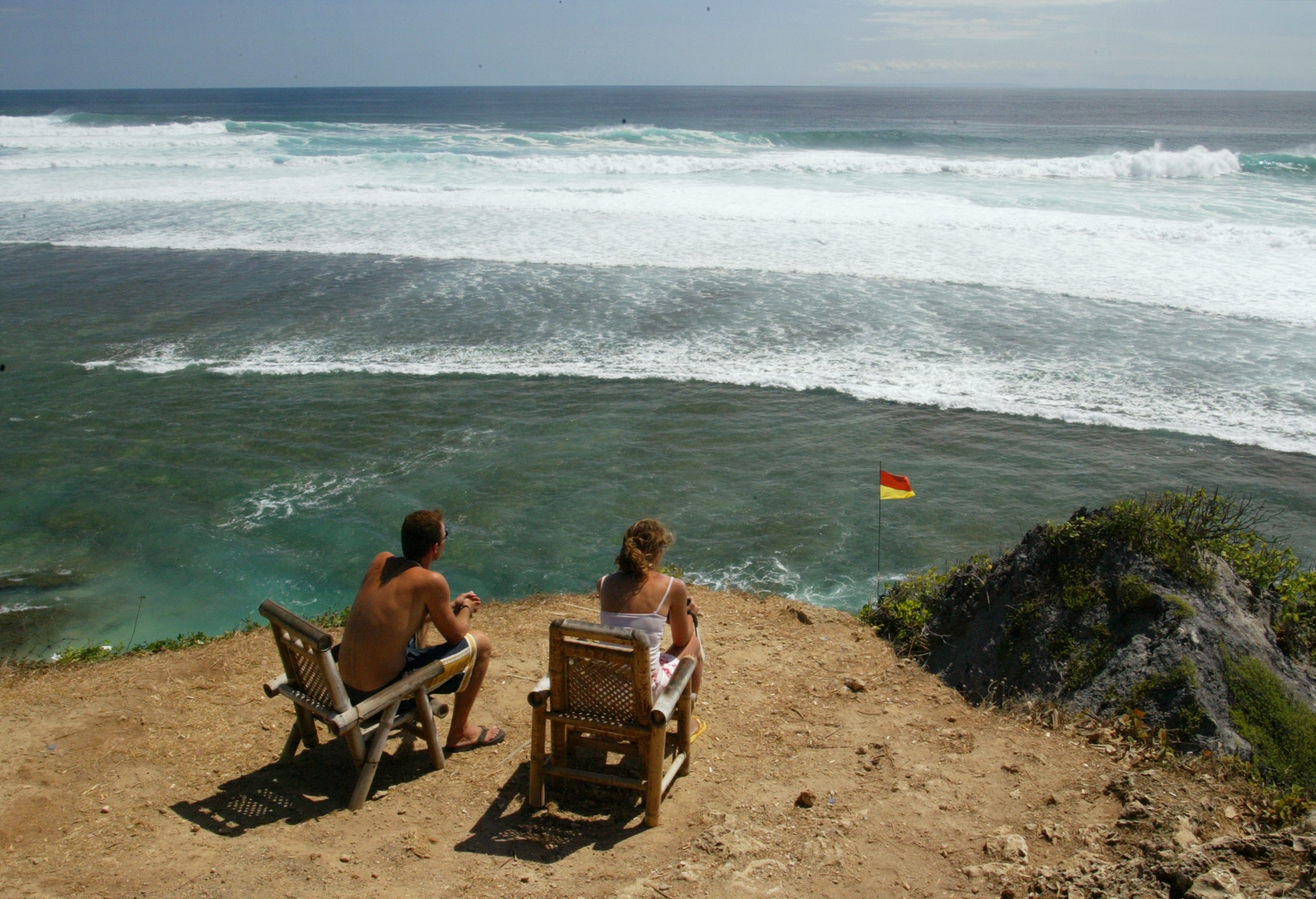 Tourists watch the waves roll in at the legendary surf break of Ulu Watu.