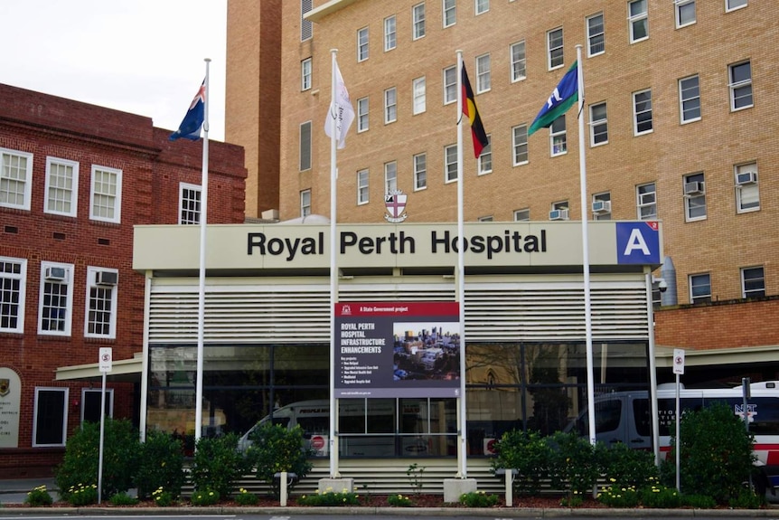 L'avant de l'hôpital Royal Perth avec une baie d'ambulance et des mâts de drapeau.