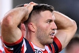 A Sydney Roosters NRL player stands with his hands on his head after South Sydney scored a try.